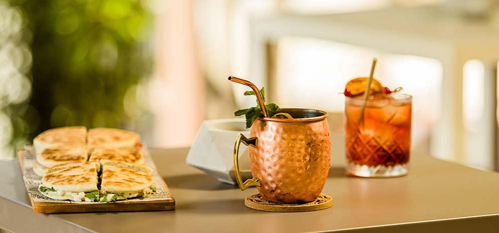 Cocktail e panini su un tavolo all'aperto, con decorazioni fresche.